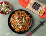 Pyszny makaron po tajsku z warzywami i kiełkami fasoli mung, obok opakowanie makaronu chow mein.