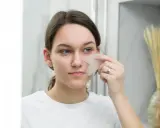 Une jeune femme utilise un gua sha pour un massage facial, un remède de grand-mère pour un visage gonflé.