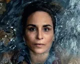 En kvinna med intensiv blick flyter i mörkt vatten, omgiven av höstlöv. En scen från veronica serie.