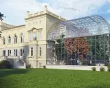 Elegancka willa z oranżerią, prawdopodobnie najdroższy hotel w Łodzi, otoczona zielonym trawnikiem.
