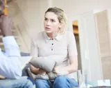 Kobieta trzyma poduszkę, rozmawiając z terapeutą. Czeka na zwolnienie od psychiatry, by móc wrócić do normalnego życia.