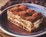 Pyszny kawałek tiramisu z mascarpone, posypany kakao, na talerzu. Idealny sprawdzony przepis na deser.