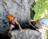 Dwie osoby w kaskach wspinają się po skale na Jurze Krakowsko-Częstochowskiej.
