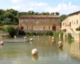 Paesini puglia con un laghetto pieno di sfere colorate, circondato da antichi edifici in pietra e vegetazione rigogliosa.
