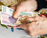 Dłonie starszej osoby liczą polskie banknoty: 100, 20 i 10 złotych.