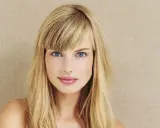 Blonde Frau mit blauen Augen und Pony. Eine Anleitung zum Pony schneiden könnte hier nützlich sein, um diesen Look zu erzielen.