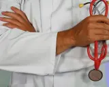 Lekarz w białym kitlu trzyma czerwony stetoskop. Dłonie skrzyżowane na piersi. Może to być pomocne przy diagnozowaniu zapalenia górnych dróg oddechowych.