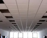 Instalación de un falso techo modular con paneles blancos y perfiles metálicos. Se aprecian huecos para iluminación o ventilación.