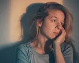 Une femme songeuse, le regard perdu, se demande : "suis je sous l'emprise d'un manipulateur test ?" Son visage exprime le doute et l'inquiétude.