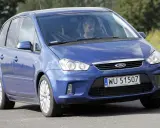 Niebieski Ford C-Max 1.6 TDCI z mężczyzną za kierownicą jedzie po drodze wśród zieleni.