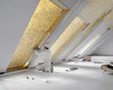 Un ouvrier installe un isolant thermique jaune texturé dans un grenier.