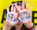 Mani con scritto "STOP OMOSESSUALITÀ" in blu, un messaggio contro il bullismo omofobico.