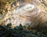 Grotta con stalattiti e stalagmiti illuminate da un raggio di sole. Un luogo magico da scoprire tra le cose da vedere vicino Alberobello.