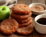 Deliciosas tortitas de manzana espolvoreadas con azúcar y canela, junto a una taza de café y una manzana verde.