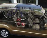 Interior de furgoneta con bicicleta azul y cascos rojos. ¡Cuidado con la multa por llevar bici dentro del coche!