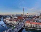 Ampio panorama berlino con la Torre della Televisione, il Duomo e il fiume Sprea. Traffico e barche animano la scena urbana.