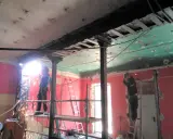 Trabajadores realizan el apeo de muro de carga con soportes metálicos y soldadura. El techo está en proceso de demolición.