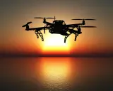 Drohne fliegt über dem Meer bei Sonnenuntergang. Bevor Sie abheben, müssen Sie Ihren Drohnenflug anmelden.