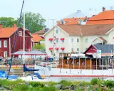 Båtar vid kajen framför hotell Vänerport i Mariestad. Röda och gula hus med tegeltak.