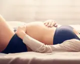 Otyły brzuch w ciąży, delikatnie głaskany dłońmi.