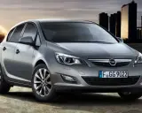 Szary Opel Astra 1.4 Turbo z nowoczesnymi światłami i felgami, na tle miejskiej panoramy i energetycznego kręgu.