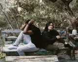 Pareja sentada de espaldas en un banco, con expresiones de angustia. El hombre se agarra la cabeza, ella mira al vacío. Un **vínculo traumático** parece separarlos en este entorno natural.