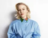 Zara Larsson, känd för sin musik, bär en blå skjorta med en färgglad krage. Hennes skivbolag har säkert hjälpt henne nå framgång.