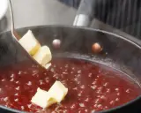 Butterstücke werden in eine köchelnde rote Sauce gegeben, um sie zu **saucen andicken** und zu verfeinern.