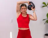 Frau trainiert mit einer Kettlebell deutsch, hebt sie über den Kopf.