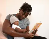Padre lee un cuento a su bebé, un momento tierno que evita la sobrecarga sensorial.
