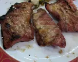 Tres trozos de lomo adobado a la parrilla, jugosos y con sal gruesa, servidos en un plato blanco con borde rojo.