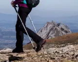 Wybierając jakie końcówki do kijków w góry, pamiętaj o stabilności. Widok na górzysty krajobraz z turystą używającym kijków trekkingowych.