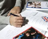 Osoba pisze ćwiczenia z angielskiego, przygotowując się do egzaminu certyfikat C2 angielski.