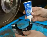 Mechanik aplikuje smar ATE Plastilube na prowadnice zacisku hamulcowego. To kluczowe, by wiedzieć, jaki smar do prowadnic hamulcowych wybrać.