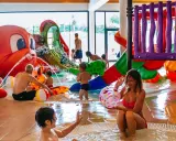 Bambini e adulti si divertono nelle **terme per bambini** con scivoli colorati e una grande attrazione a forma di polpo che spruzza acqua.