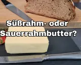 Ein Block Butter liegt neben Brot und Kräutern. Die Frage: Süßrahm- oder Sauermilchbutter?