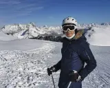 Narciarz w kasku i goglach na tle ośnieżonych gór.