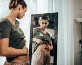 Kobieta zmartwiona dotyka brzucha, zastanawiając się, czy przy menopauzie boli brzuch.