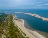 Piękny **urlop w Polsce** nad morzem. Piaszczysta plaża, zieleń i błękit wody tworzą malowniczy krajobraz.