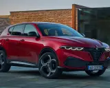 Czerwone Alfa Romeo Tonale na tle nowoczesnej architektury. Sprawdź aktualną alfa romeo tonale cena i konfigurację.