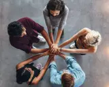 Un gruppo di persone unisce le mani, un'immagine che incarna la social definizione di unità e collaborazione.