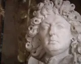 Marmorstatue eines Mannes mit Lockenperücke, die an die Pracht des Absolutismus erinnert.