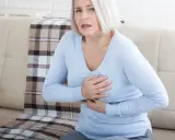 Kobieta z bólem w klatce piersiowej, zastanawia się, czy zwapnienia są groźne.