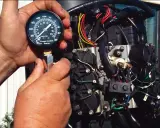 Mains d'un mécanicien utilisant un testeur de compression sur un moteur hors-bord. Le moteur se lance mais ne démarre pas essence.