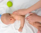Dziecko na brzuchu ćwiczy mięśnie. Brak tych ćwiczeń może mieć konsekwencje dla rozwoju. Zabawki obok.