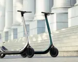Deux trottinettes électriques modernes, idéales pour votre application trajet trottinette. L'une argentée, l'autre vert émeraude, sur des marches devant des colonnes.
