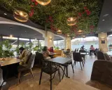 Intérieur d'un bar à desserts avec plafond végétalisée, lumières suspendues et tables occupées.
