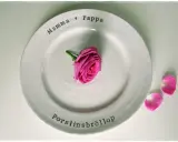 En vit tallrik med texten "Mamma ♡ Pappa" och "Porslinsbröllop". En rosa ros ligger i mitten. Ett vackert minne för de som varit gifta i 20 år.