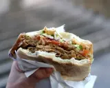 Ręka trzyma pysznego kebaba z mięsem, warzywami i chrupiącą surówką do kebaba.