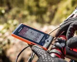 Pomarańczowy licznik rowerowy Sigma ROX 12.0 Sport pokazuje dystans 39.8 km i wysokość 282 m. Rękawiczka rowerowa na kierownicy.